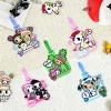 Five tokidoki cartoon silicone luggage tags in pink purple green and blue on knit blanket, collectible baggage tags for fans.