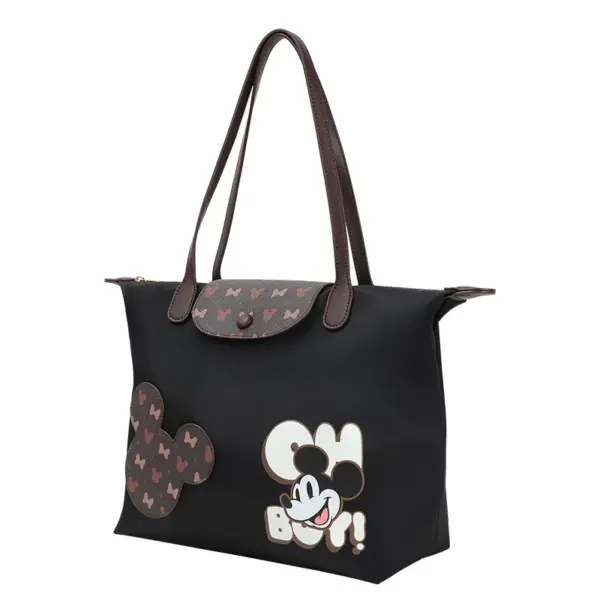 Black nylon tote bag featuring Mickey Mouse "Oh Boy" print and brown leather handles, side angle view.