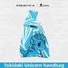 Sky blue MESUCA x Tokidoki knit wristlet bag with woven unicorn pattern and wide wrist strap on a wave background.