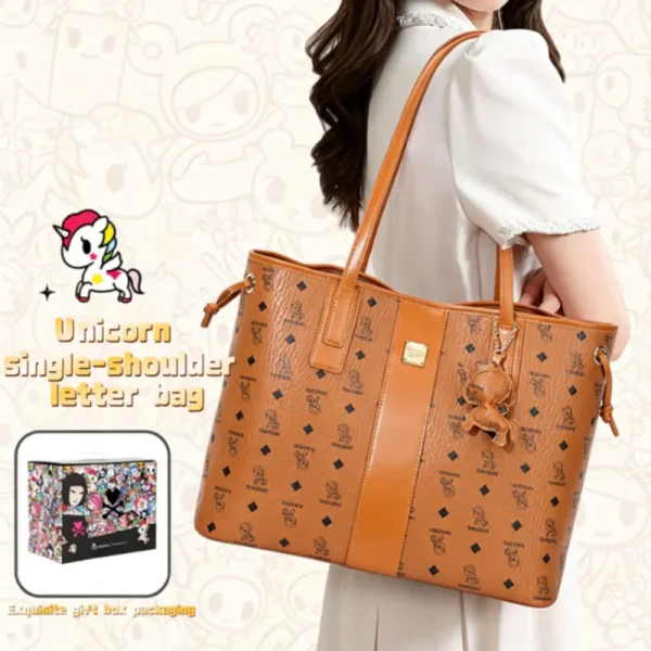 Woman in white blouse carrying a cognac brown Tokidoki unicorn print vegan leather tote bag on her shoulder with gift box.