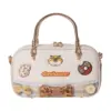 Direct front shot of a pastel cream mini tote bag with embroidered cheetah face, donut patch, lace trim, bow tie, crochet flowers, and "CLAWHAUSER" text.