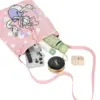 Flat lay showing a pink polka dot knit bag holding a phone, umbrella, perfume, and makeup essentials.