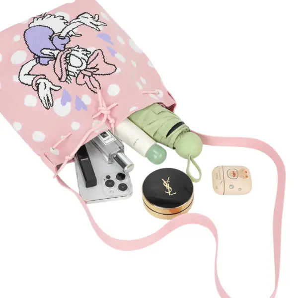 Flat lay showing a pink polka dot knit bag holding a phone, umbrella, perfume, and makeup essentials.