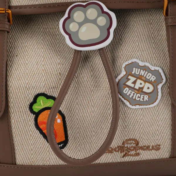 Close-up showing the embroidered carrot pen loop, paw print badge, and "Junior ZPD Officer" patch on canvas fabric.