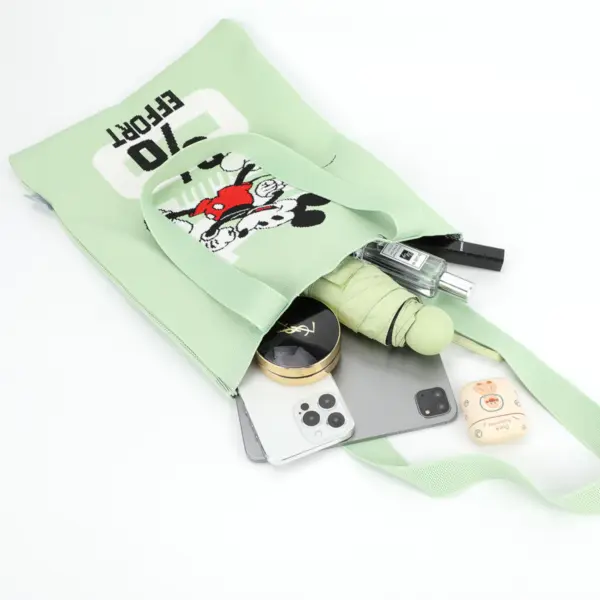 Flat lay showing a light green woven tote bag holding a tablet, phone, umbrella, perfume, and makeup essentials.