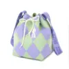Angled view of a small knit drawstring purse with purple and green checks and a wide shoulder strap.