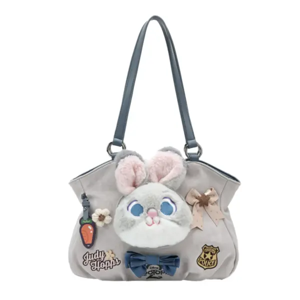 Front view of a grey suede-like shoulder bag featuring a plush Judy Hopps face, denim bow, and carrot charm accessory.